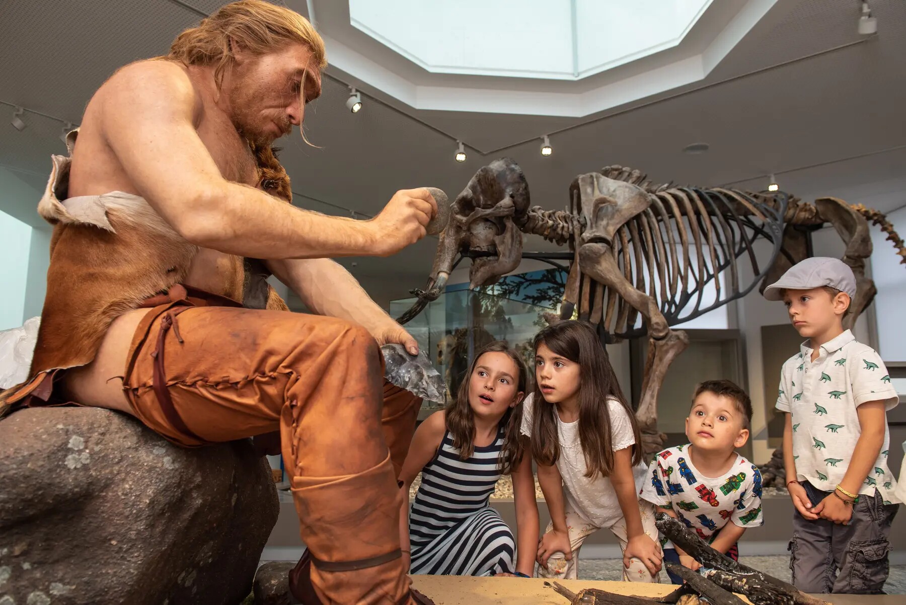 Neandertaler-Darsteller erklärt Kindern ein Steinzeitwerkzeug im Naturmuseum Dortmund